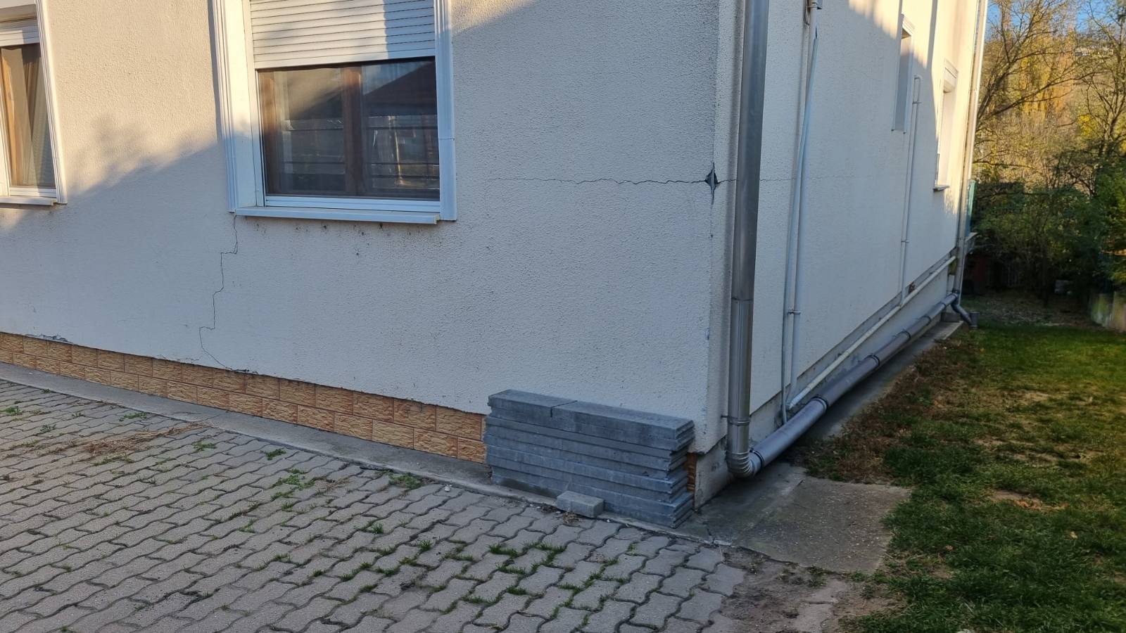 Jól látható, lépcsőzetes repedések a homlokzaton egy ablak alatt