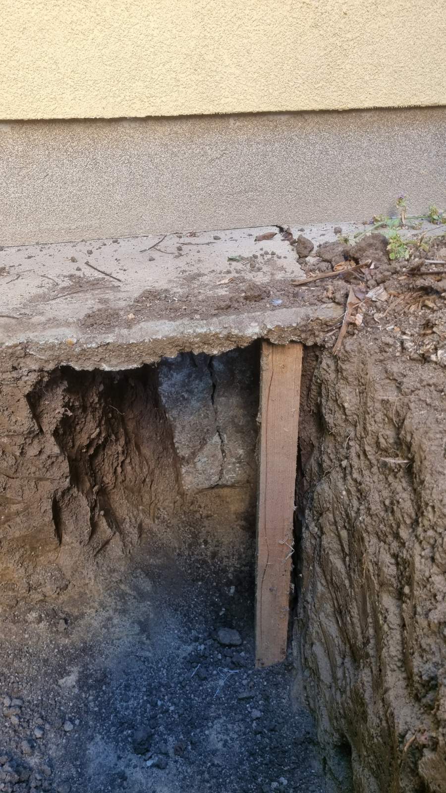 2. kép: A lábazat mellett kiásott kutatógödör. Jól látszik a terepszinttől mért alapozási mélység, valamint a gödör falának összefüggő, agyagos szerkezete